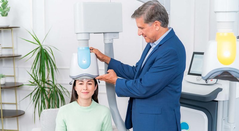 Clinician preparing a smiling patient for a Deep TMS session