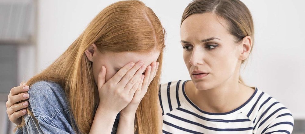 One woman comforting another who covers her face